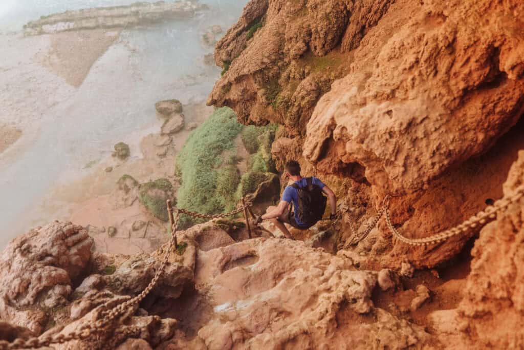 Climbing down Mooney Falls, using the chains almost to the ladder